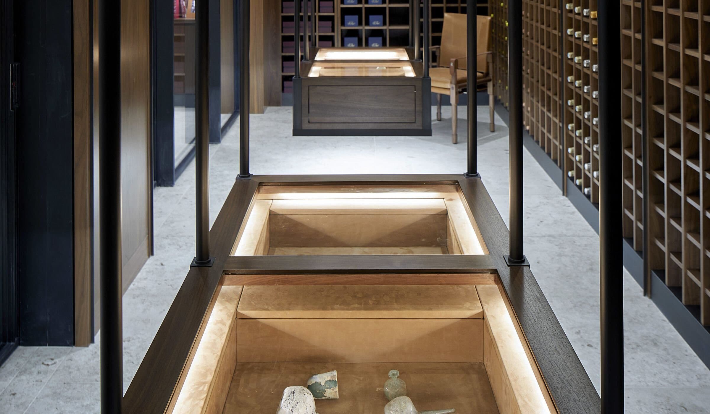 Walnut display cases hung from steel rods down the center of a wine library