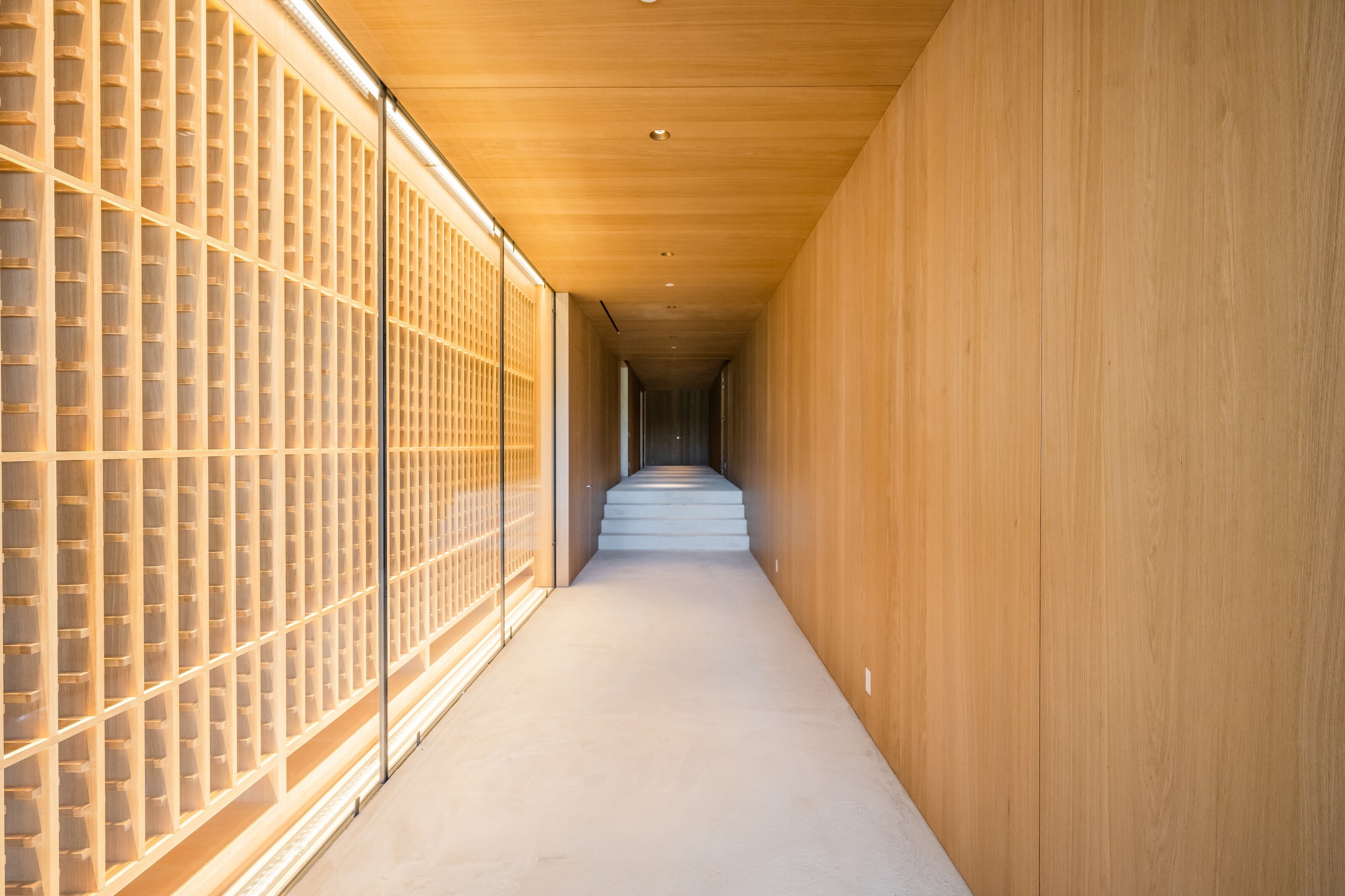 A corridor between oak paneling and a backlit wood lattice screen