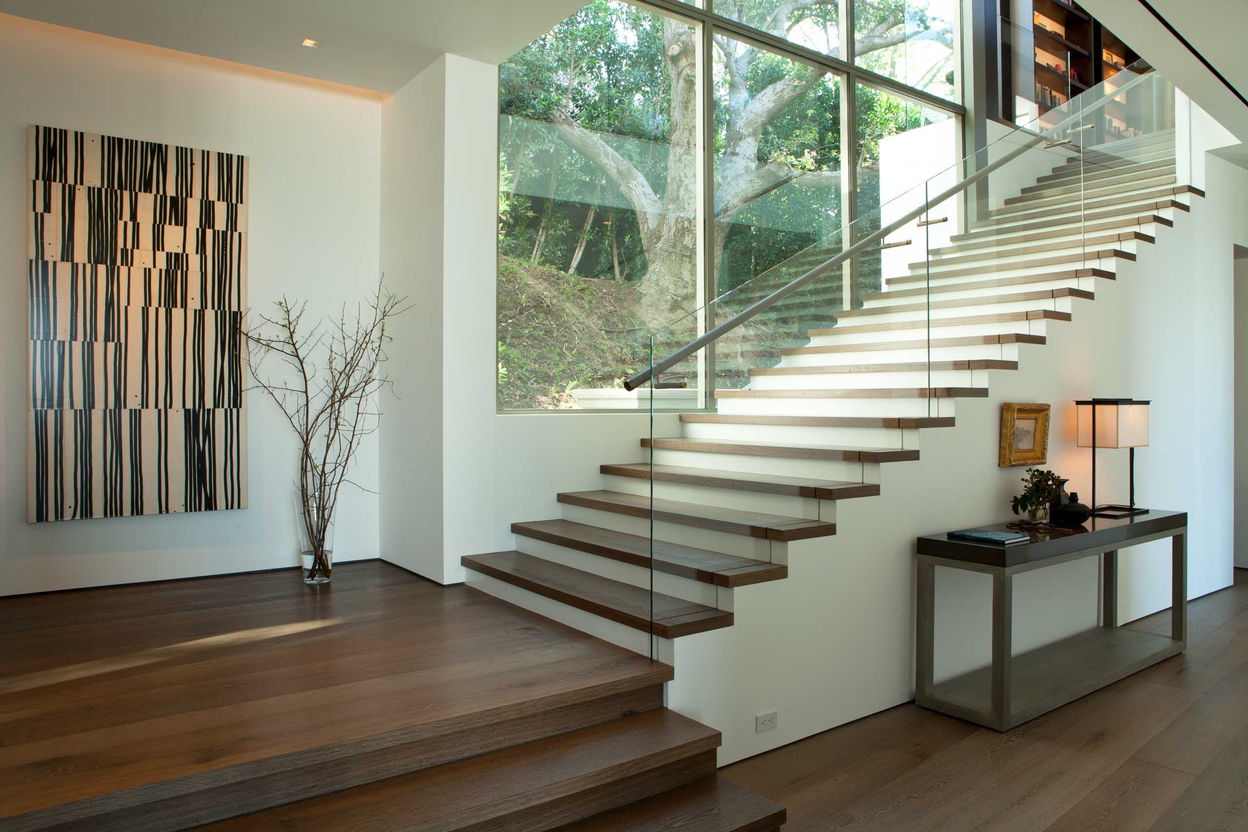 A stair of floating wood treads beside a sculptural wood wall panel