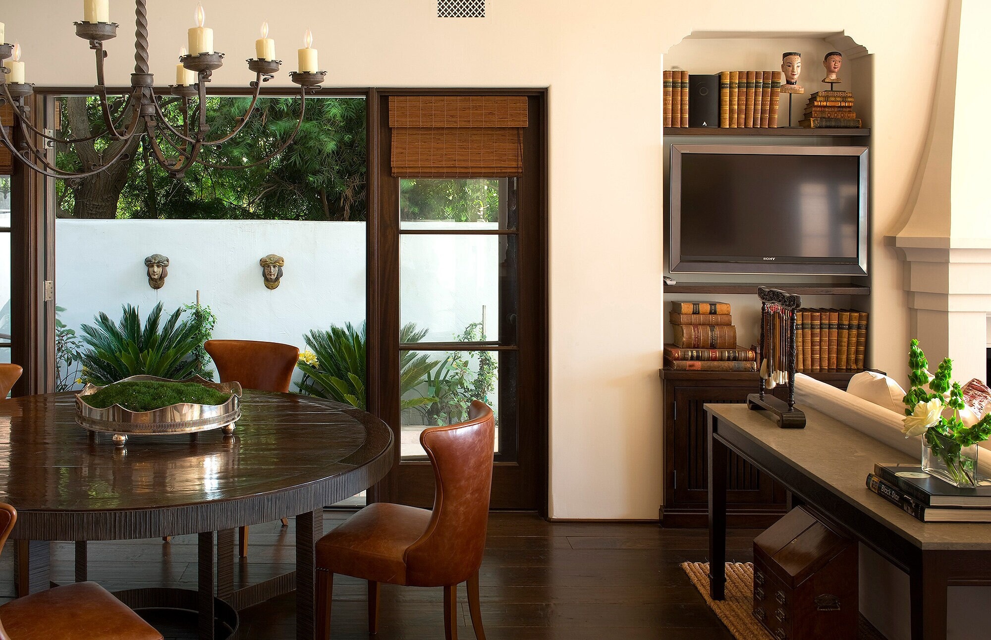 A dining room with wood shelving and a carved ceiling, the garden through the doors