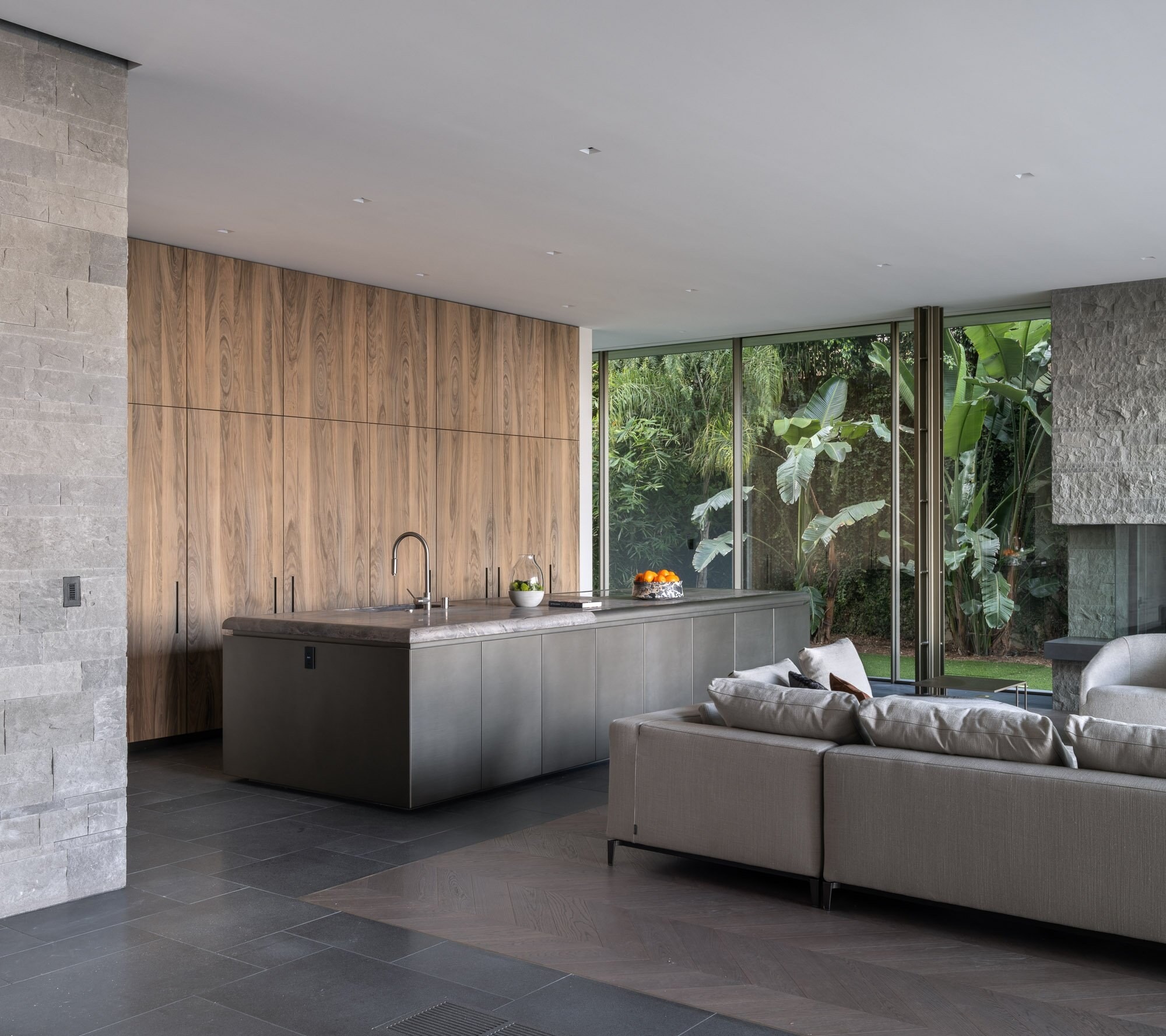 A kitchen wall of walnut paneling beside a stone island