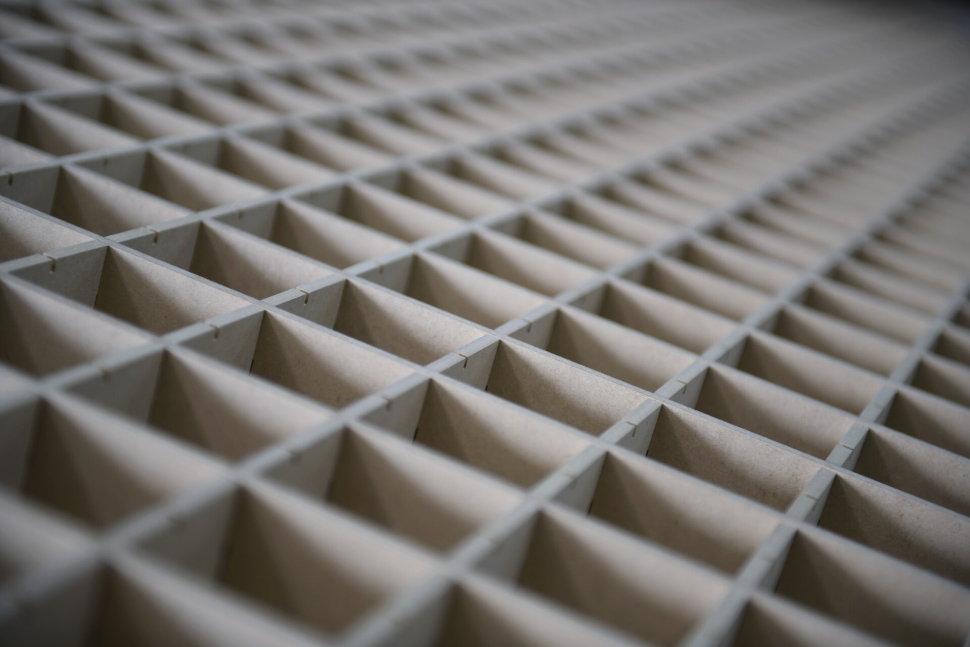 A precision-cut grid of interlocking slotted panels, receding into soft focus