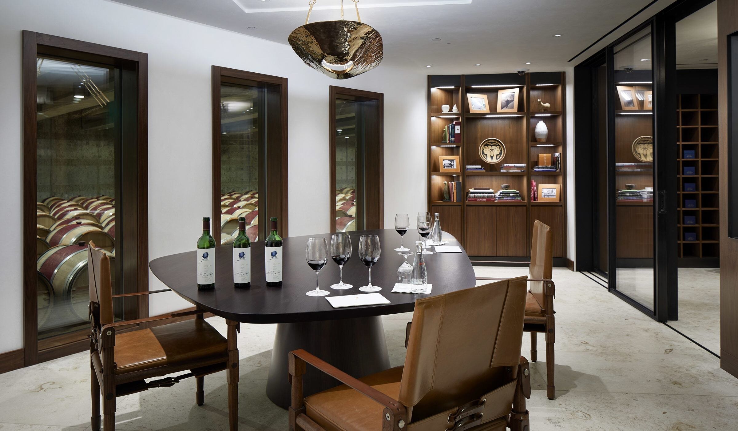 A tasting room with walnut shelving and glazed openings onto the barrel room