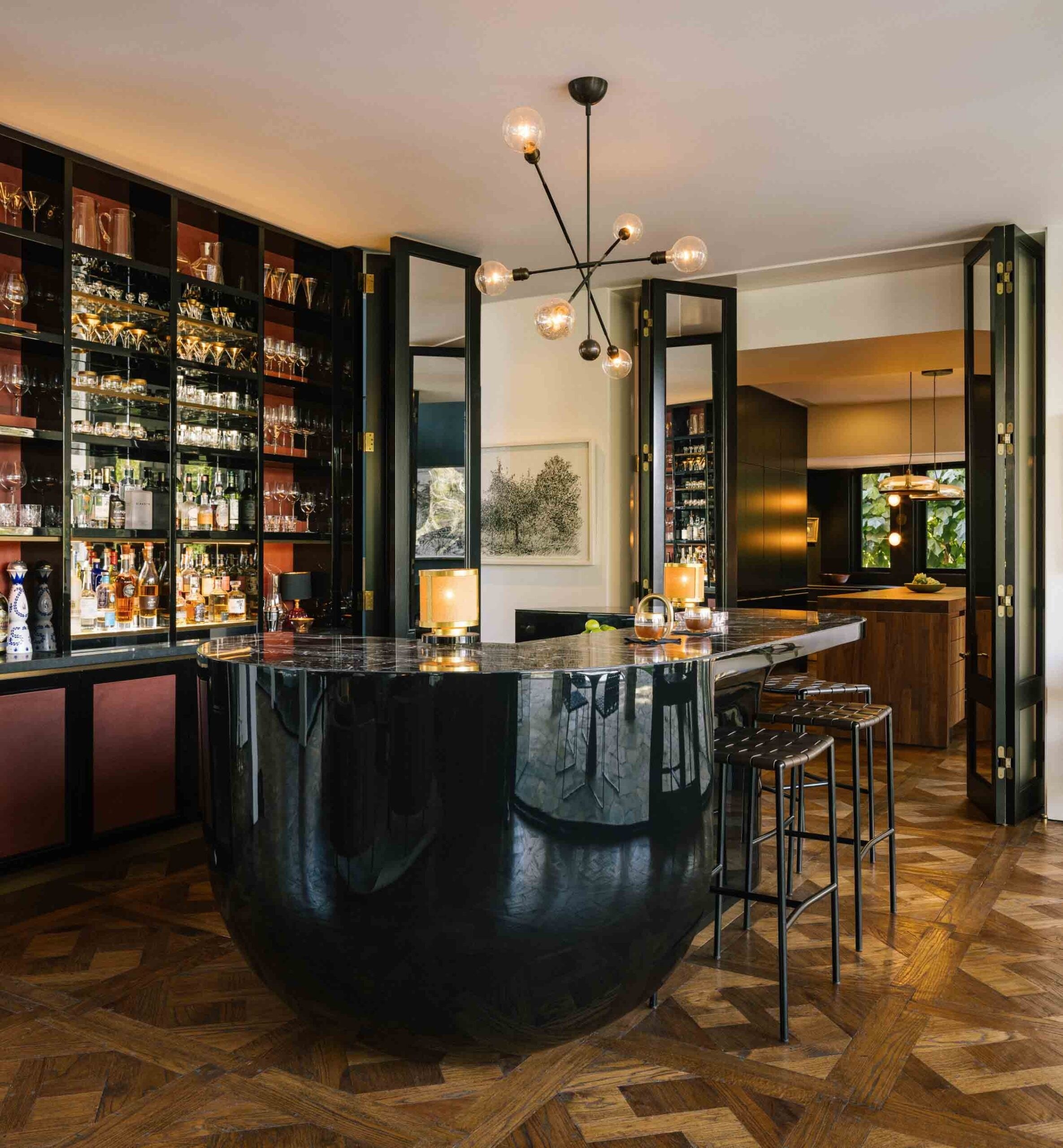 A bar of dark shelving around a curved black counter, lit bottles on every shelf