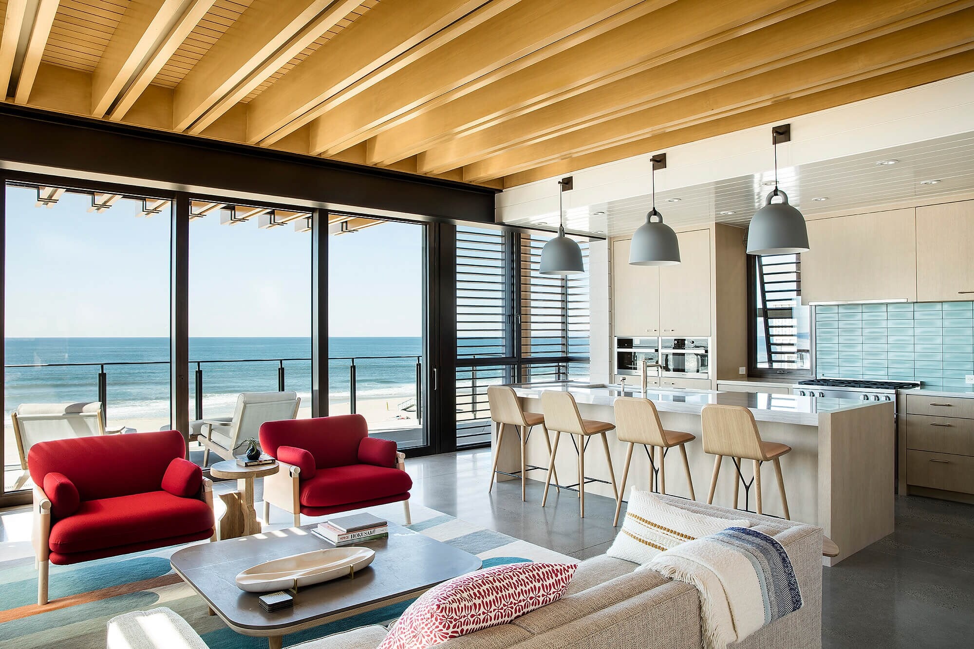 A beach house living room under a ceiling of wood slats, the ocean beyond